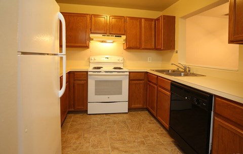 A kitchen with a white refrigerator, black dishwasher, and a white stove top oven.
