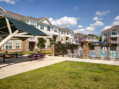 A sunny day at a residential complex with a pool and picnic tables.