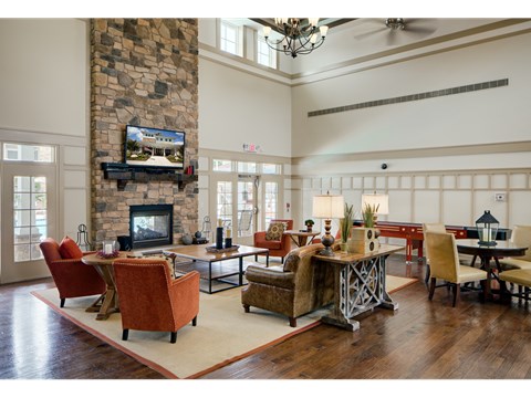 A living room with a stone fireplace and a television above it.