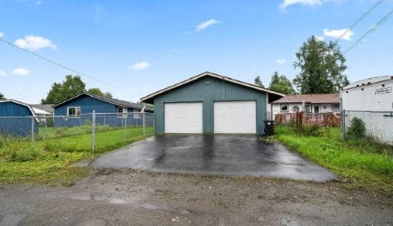 a blue garage with a white door on a driveway