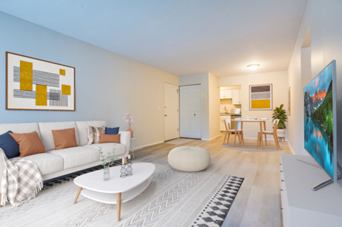 a living room with a couch and a coffee table and a kitchen in the background