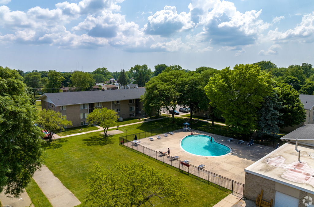 an aerial view of a swimming pool with trees and a building in the background