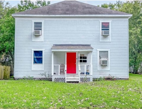 A white house with a red door and a blue window.