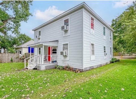 A small white house with a red door and a blue awning.