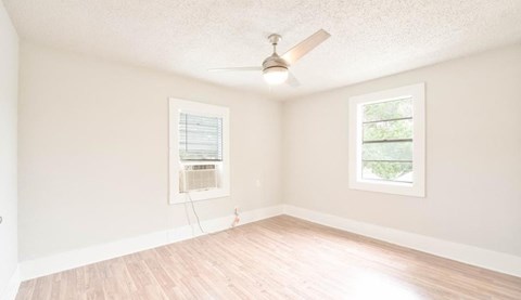 A room with a window and a fan on the ceiling.