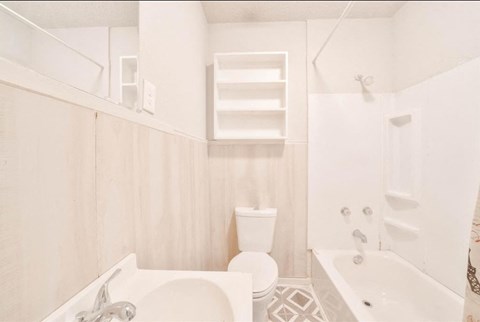 A white bathroom with a toilet, sink, and bathtub.