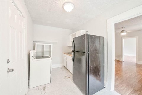 A white fridge in a room with a door and a window.