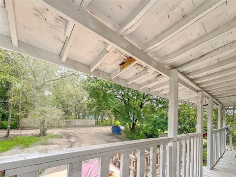 A porch with a white railing and a roof with some damage.