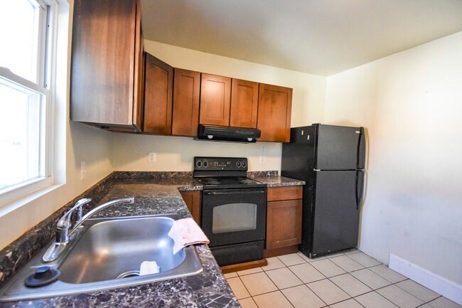 A kitchen with black appliances and brown cabinets.