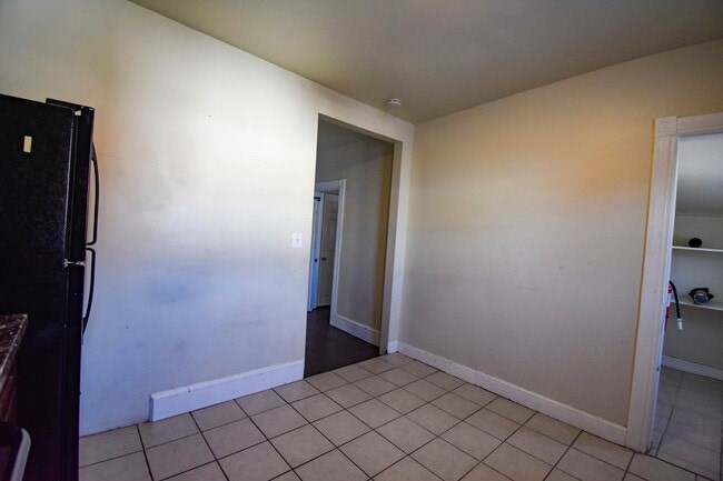 A kitchen with a black fridge and white walls.