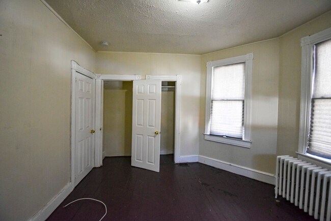 A room with a white door, a window, and a radiator.