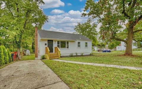 a small white house with a sidewalk in front of it