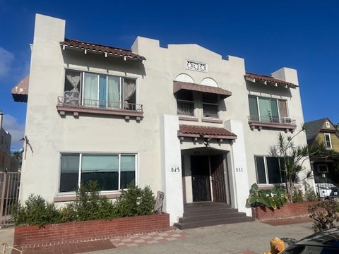 A white two-story house with a brown roof and a brown door.