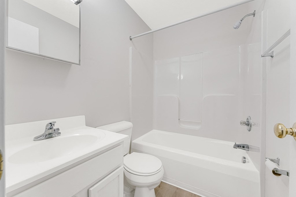 A white bathroom with a toilet, sink, and bathtub.