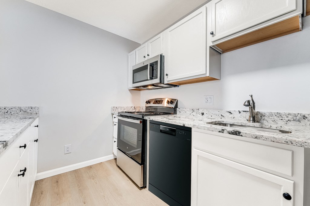A kitchen with a black oven and white cabinets.