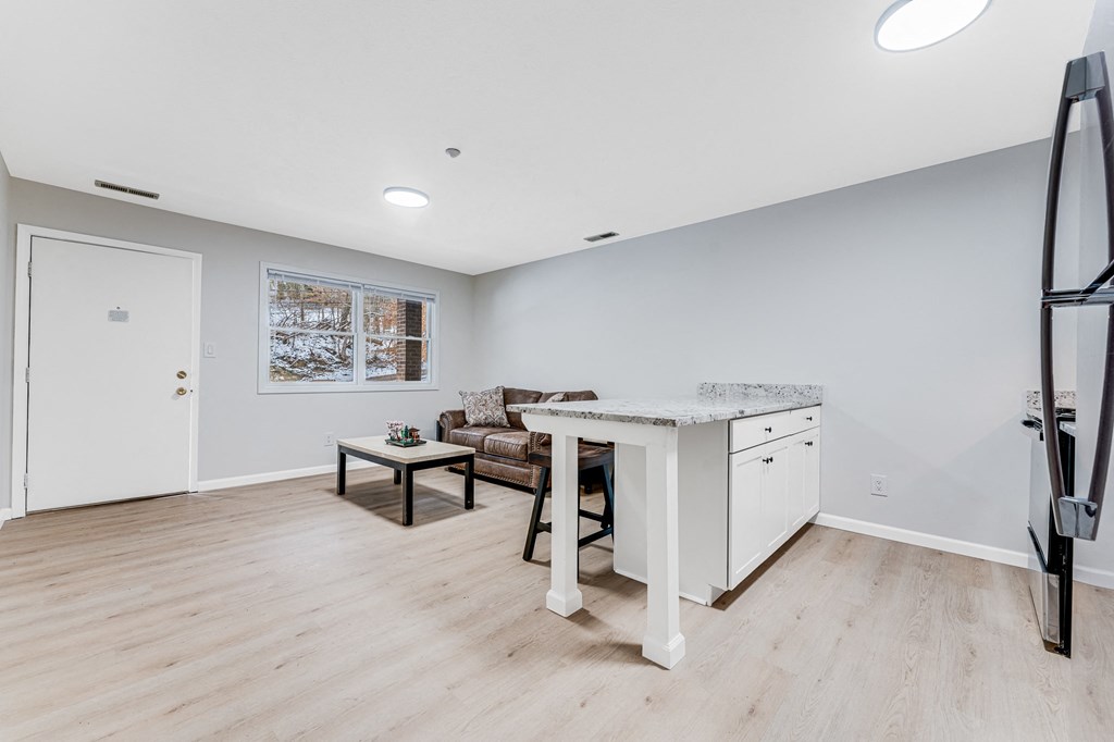 A spacious room with a white desk and a brown couch.
