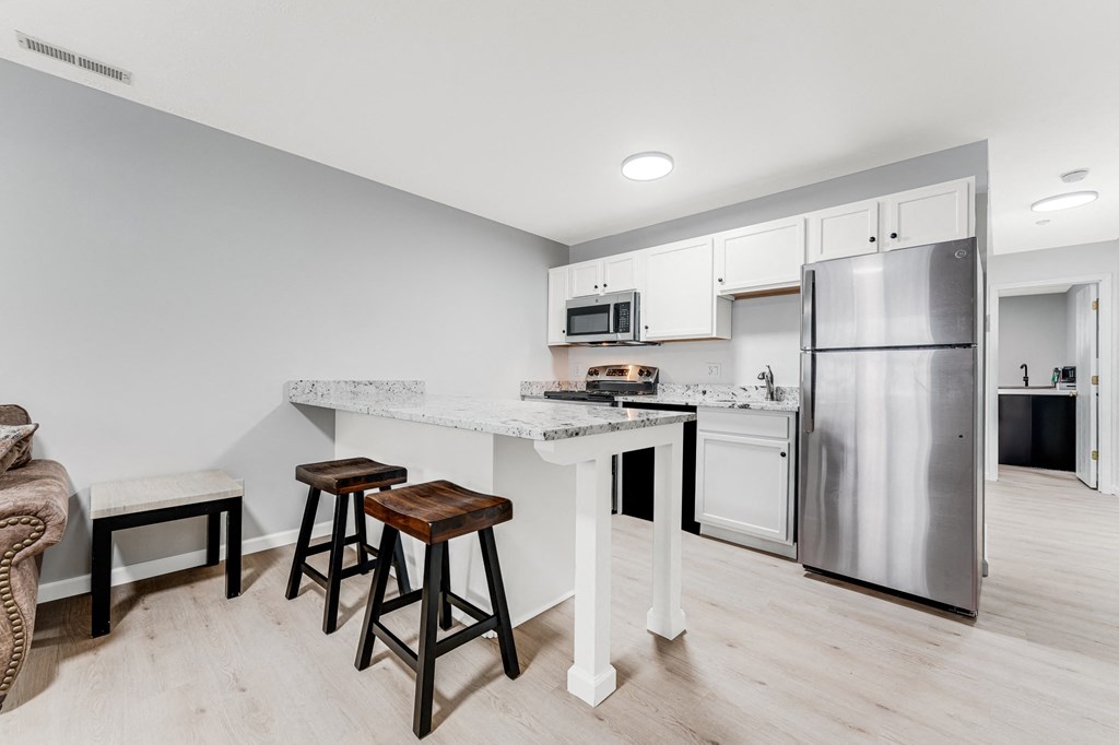 A kitchen with a refrigerator, microwave, and oven.