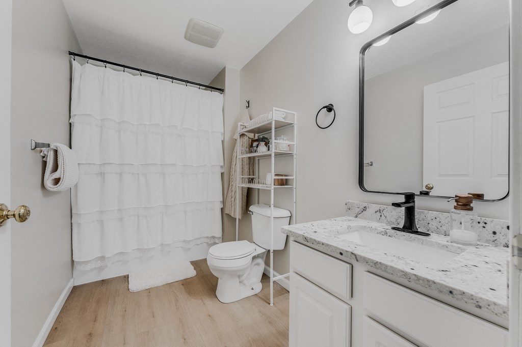 A white bathroom with a toilet, sink, and shower.