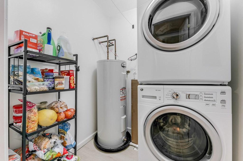 A laundry room with a washer and dryer, a shelf with food items, and a water heater.