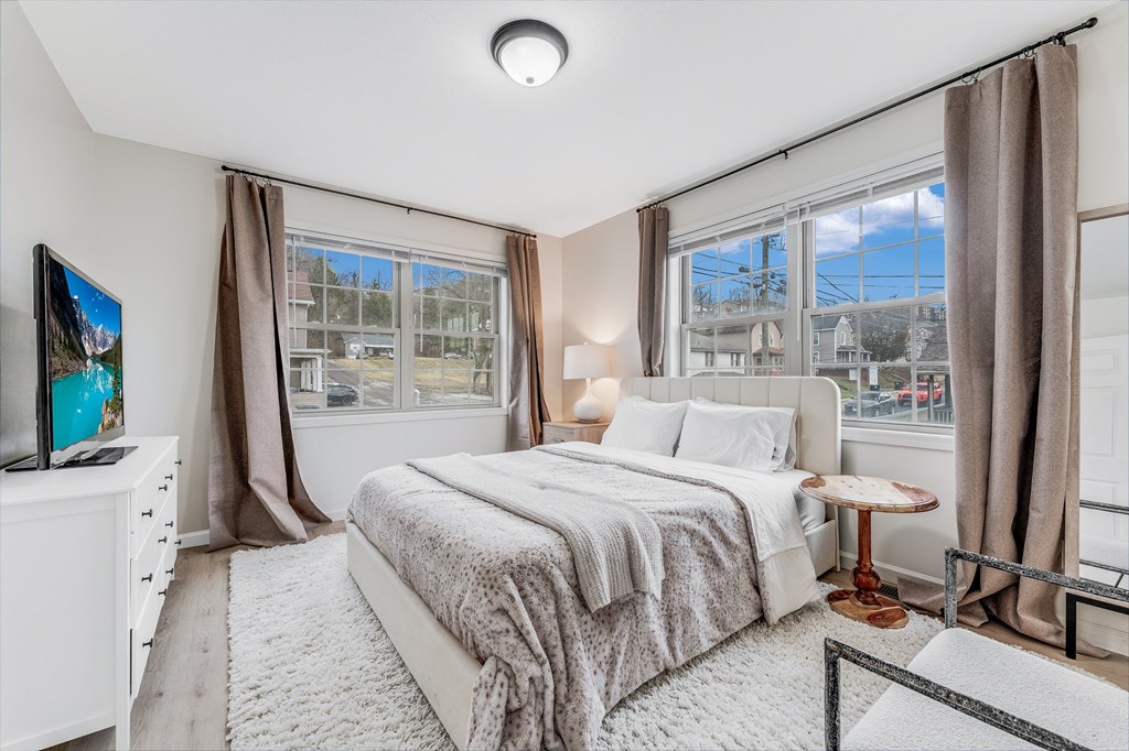 A bedroom with a large bed and a television on a white dresser.