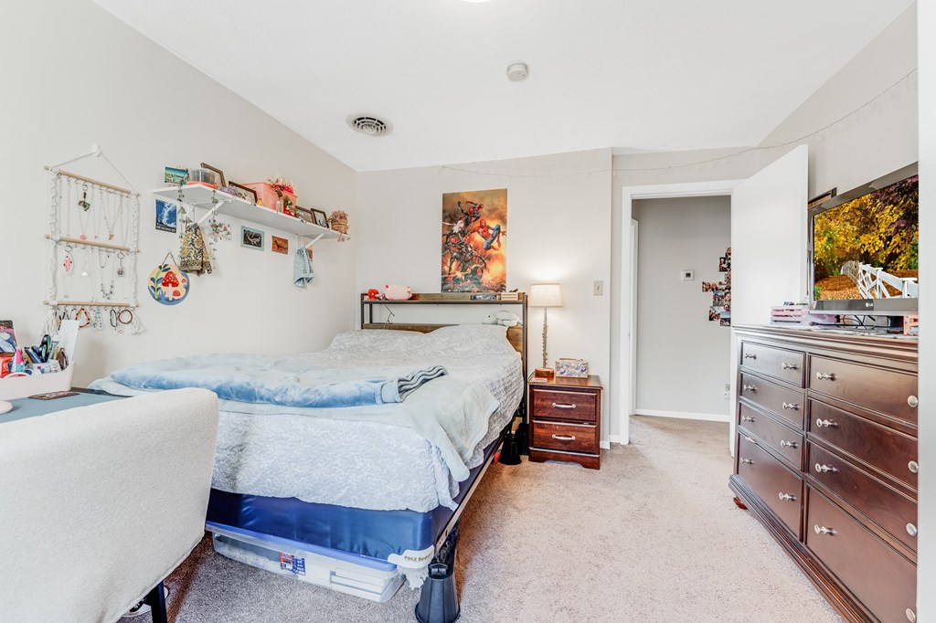 A bedroom with a bed, dresser, and chair.