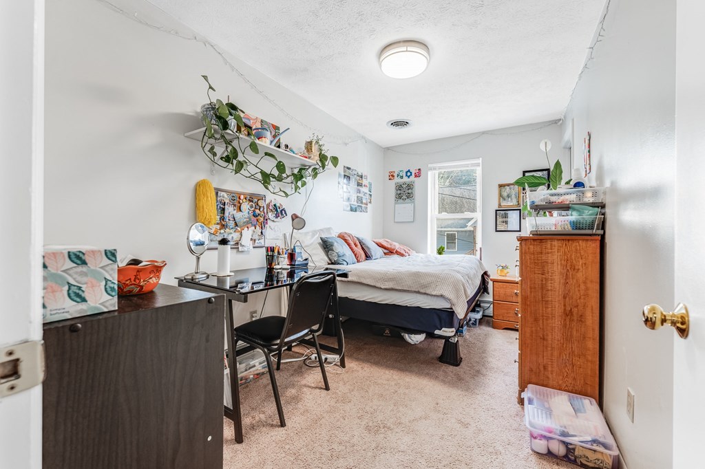 A bedroom with a bed, desk, and chair.