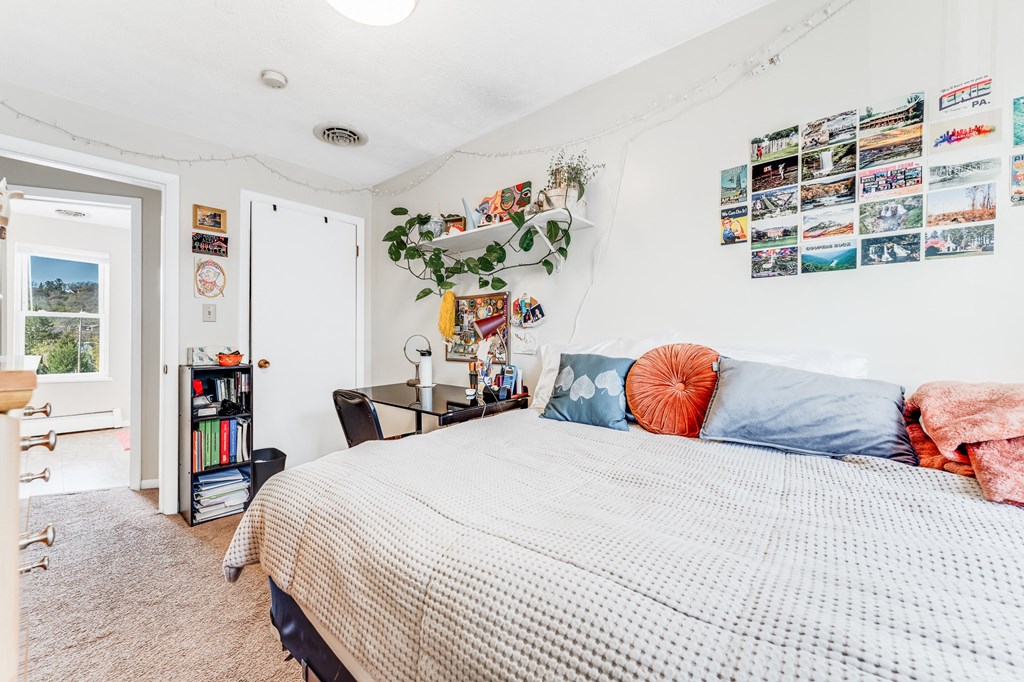 A bedroom with a bed, a desk, a chair, a bookshelf, and pictures on the wall.