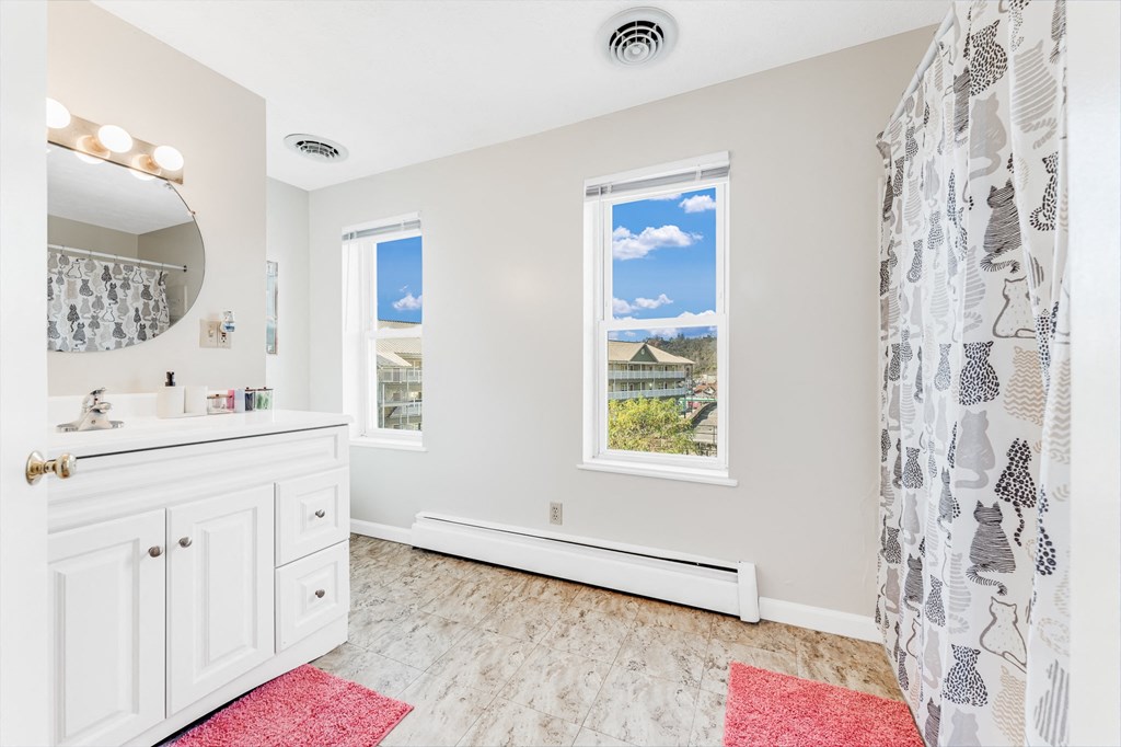 A bathroom with a window showing a view of a house and trees outside.