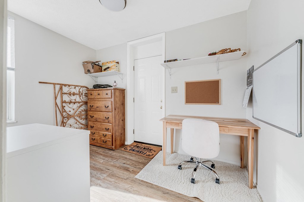 A white chair is in front of a wooden desk in a room.