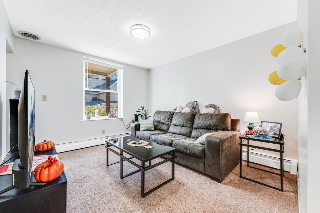 A living room with a grey couch and a glass coffee table.