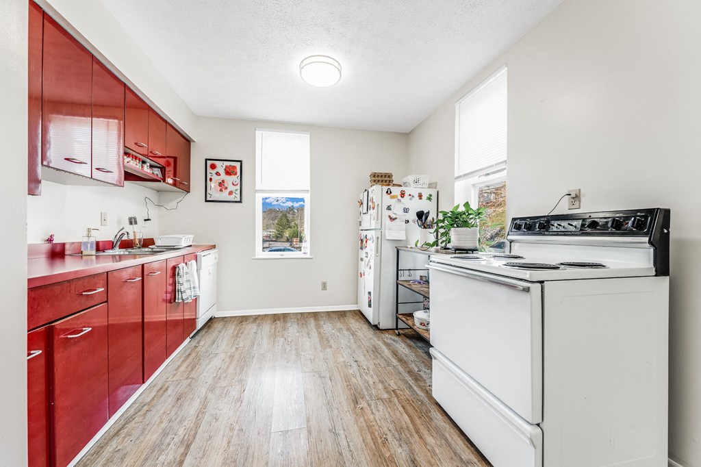 A kitchen with red cabinets and a white fridge.