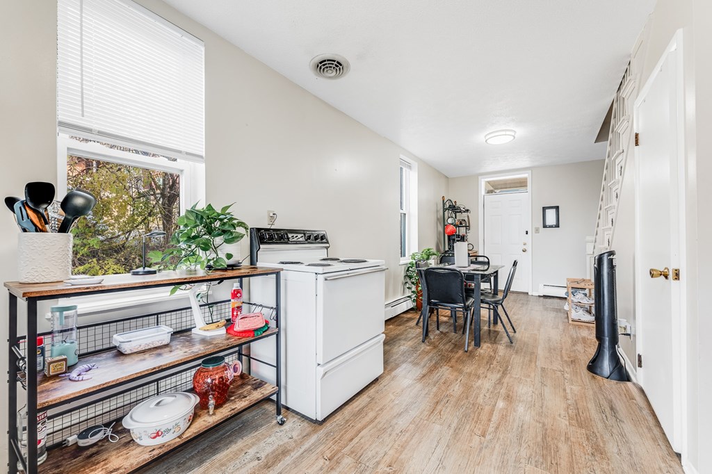 A kitchen with a white fridge, a table with chairs, and a window with a view of trees.