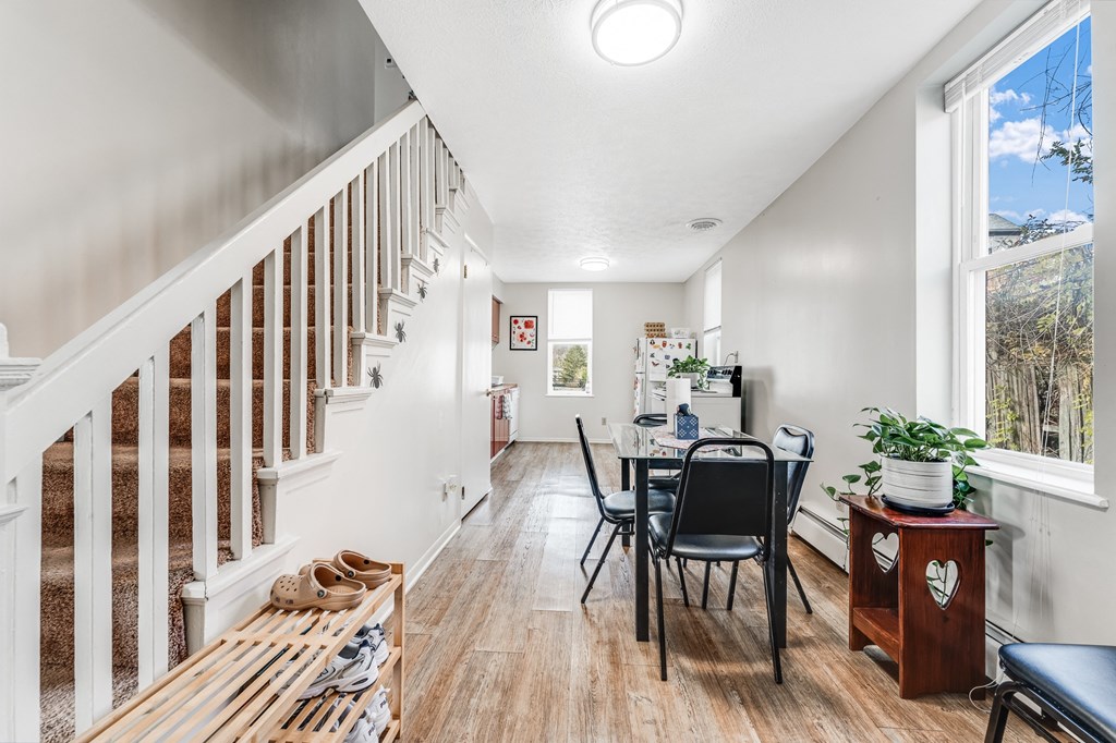 A white room with a wooden staircase and a dining table with chairs.