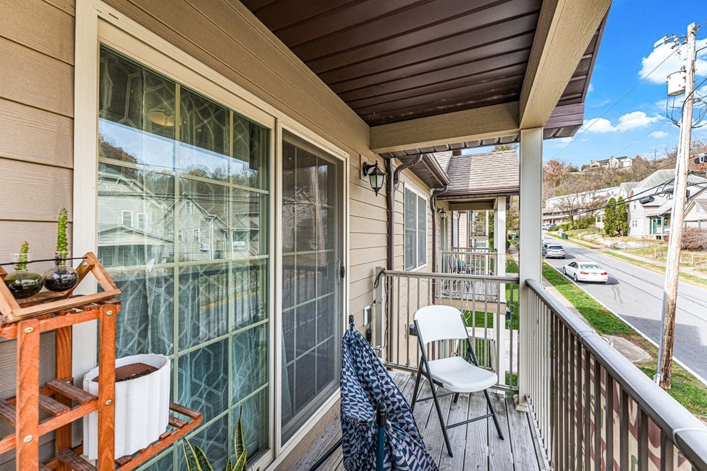 A balcony with a chair and a table with a plant on it.