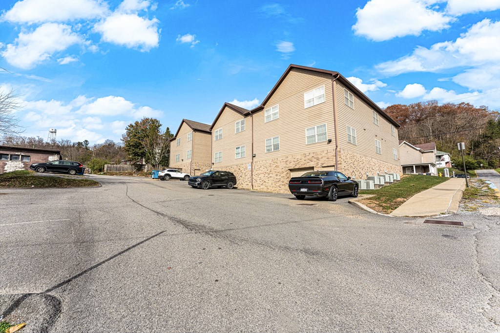 A parking lot in front of a building with cars parked.