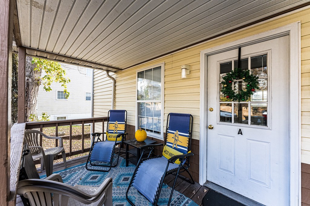 A white door with a wreath on it is on the right side of a porch.