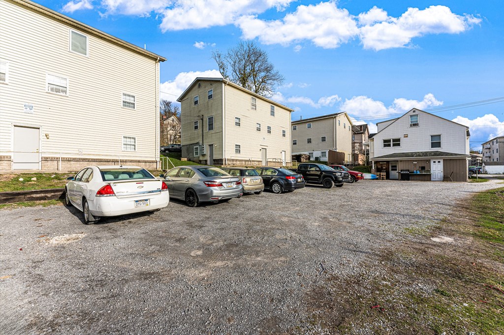 A parking lot with several cars and buildings in the background.