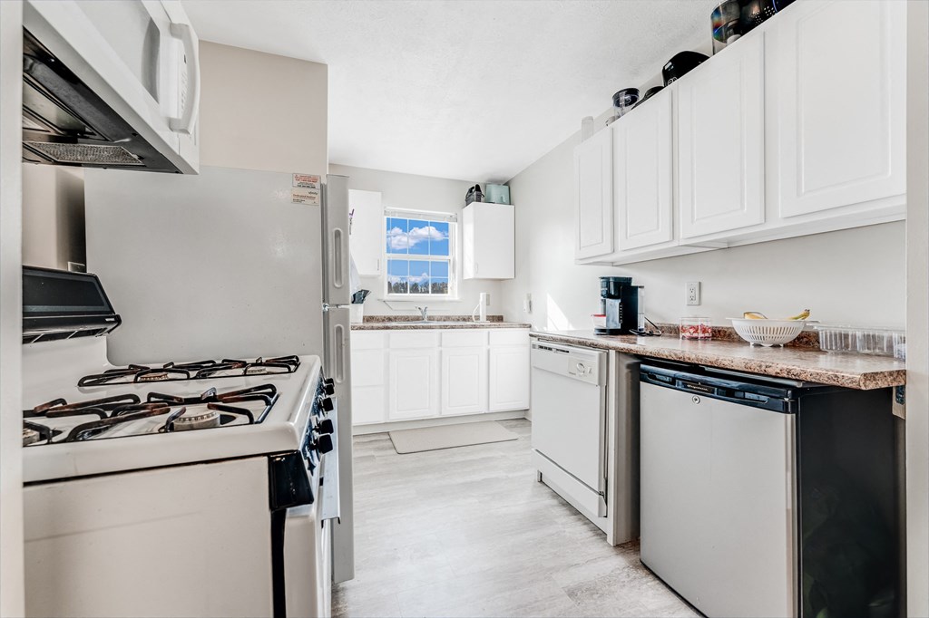 A kitchen with white cabinets and a stove top oven.