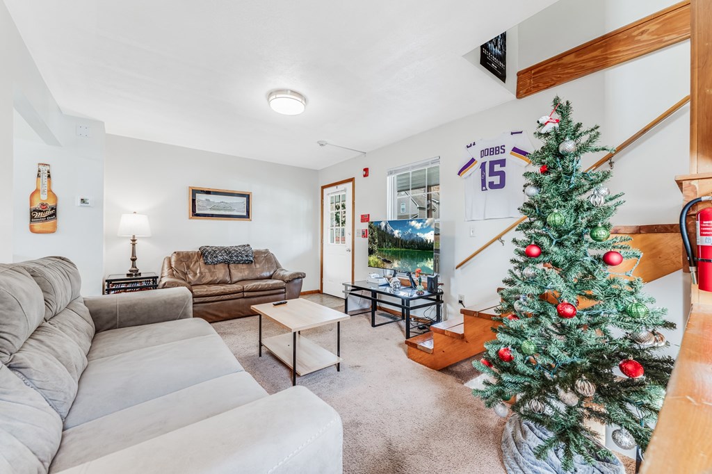 A living room with a Christmas tree and a jersey on the wall.