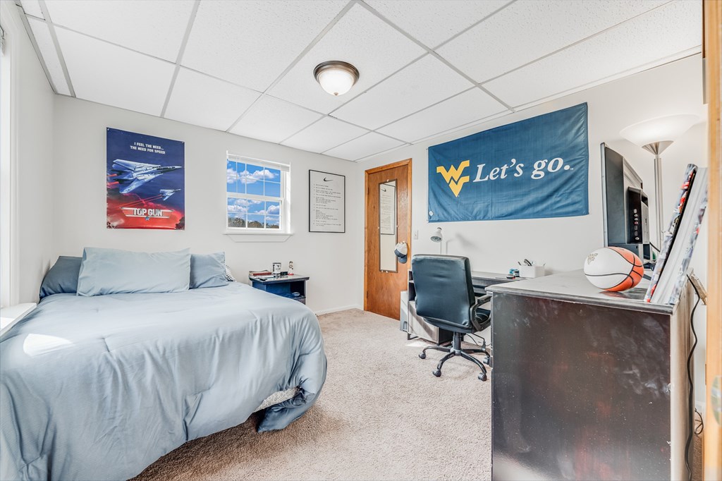 A bedroom with a bed, desk, chair, and a banner on the wall.