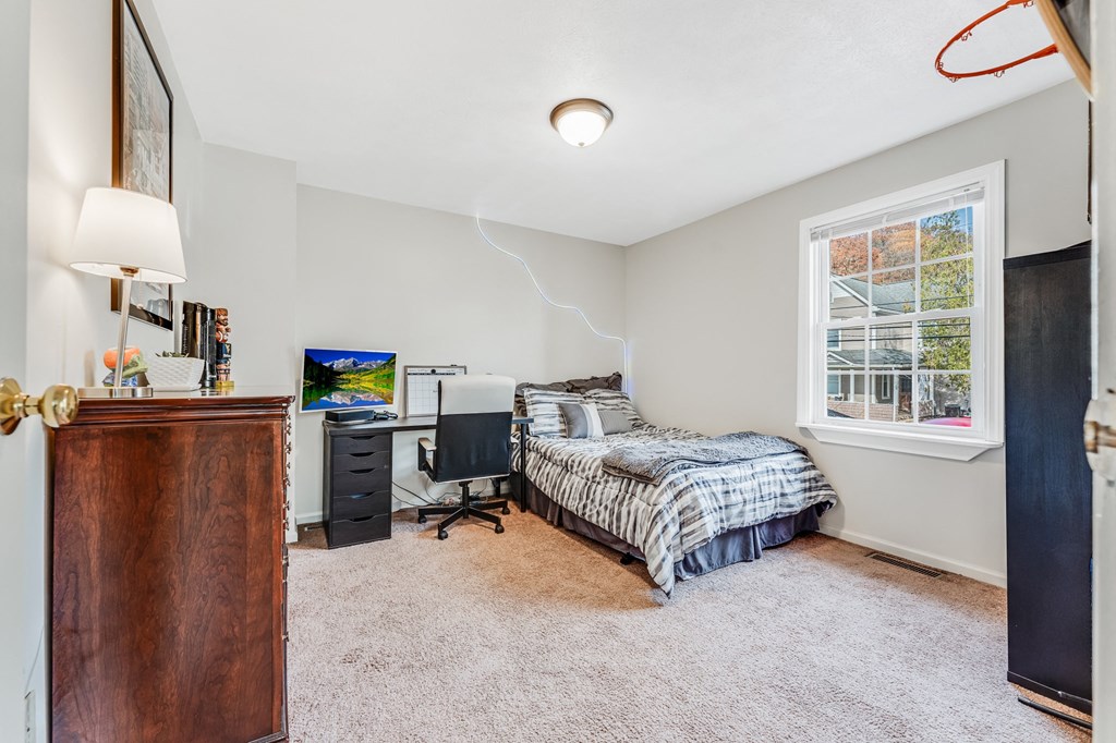 A bedroom with a bed, desk, and chair.