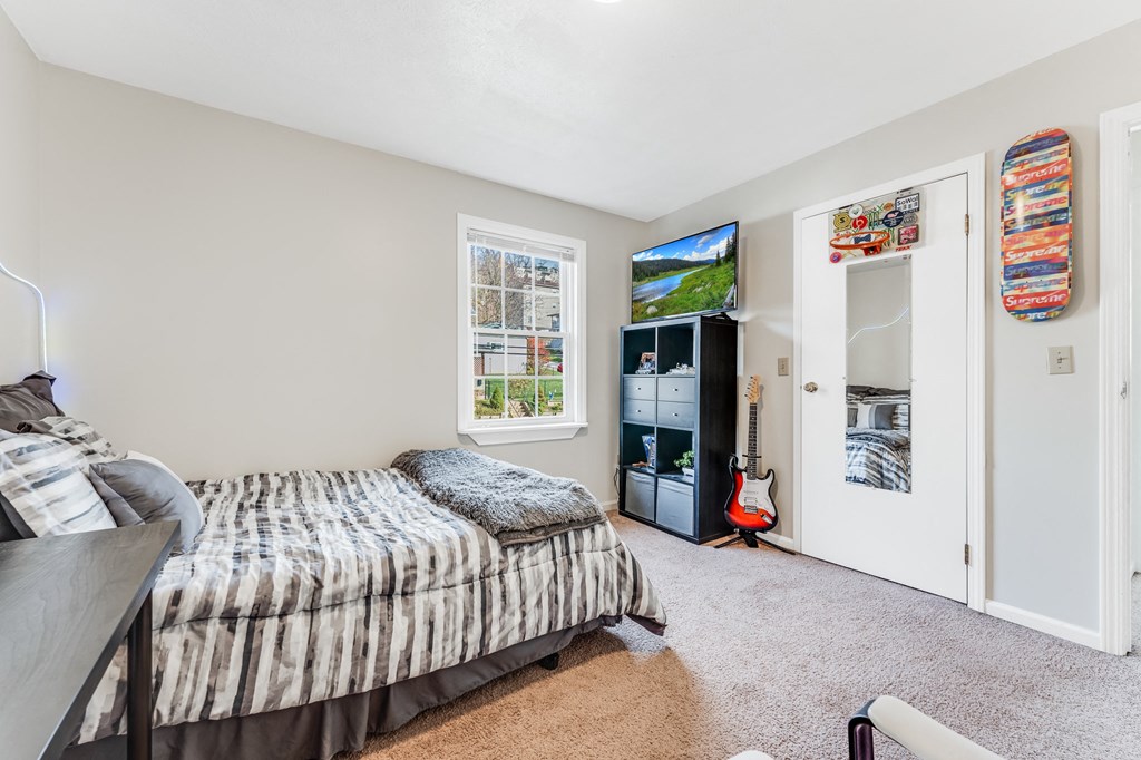A bedroom with a bed, a TV, and a guitar.