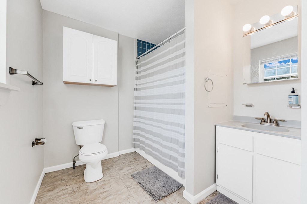 A white toilet sits in a bathroom next to a sink.