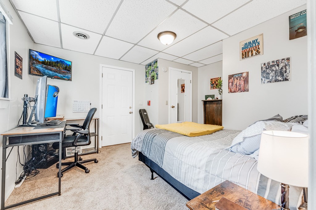 A bedroom with a bed, desk, and chair.