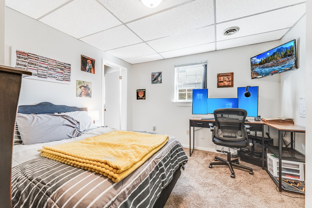 A bedroom with a bed, desk, and chair.