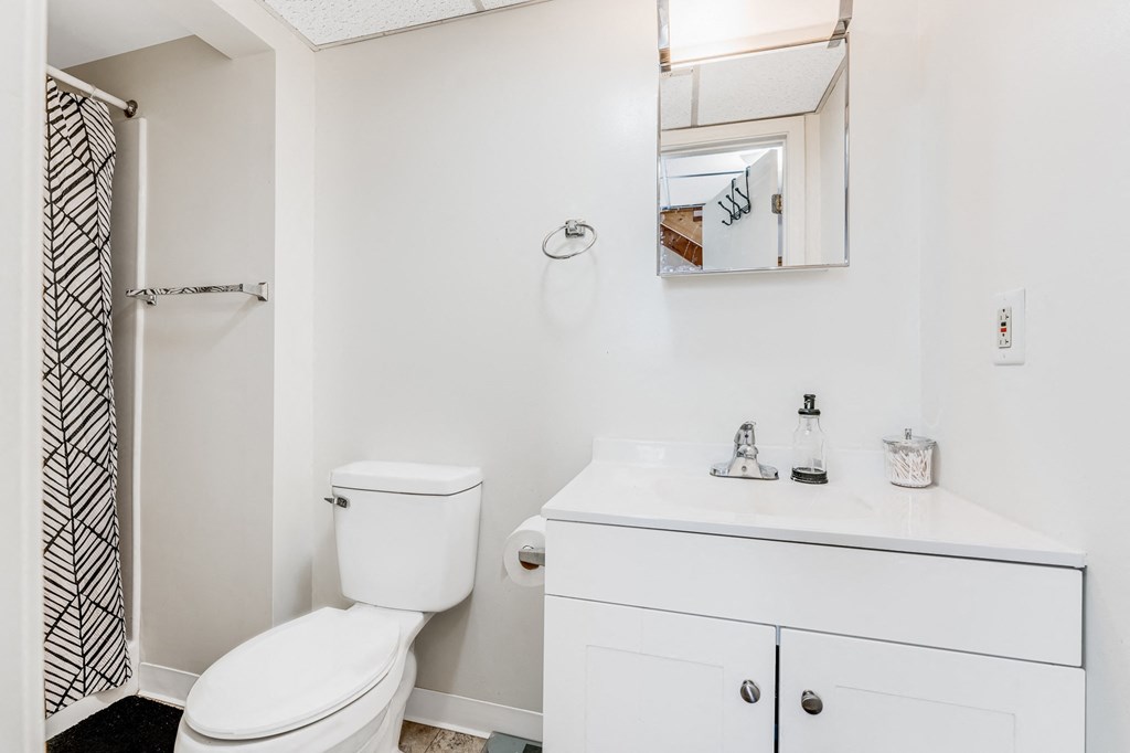 A white toilet sits next to a white sink in a small bathroom.