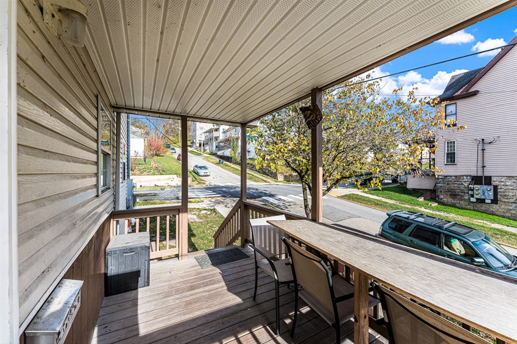 A wooden deck with a table and chairs overlooking a street.