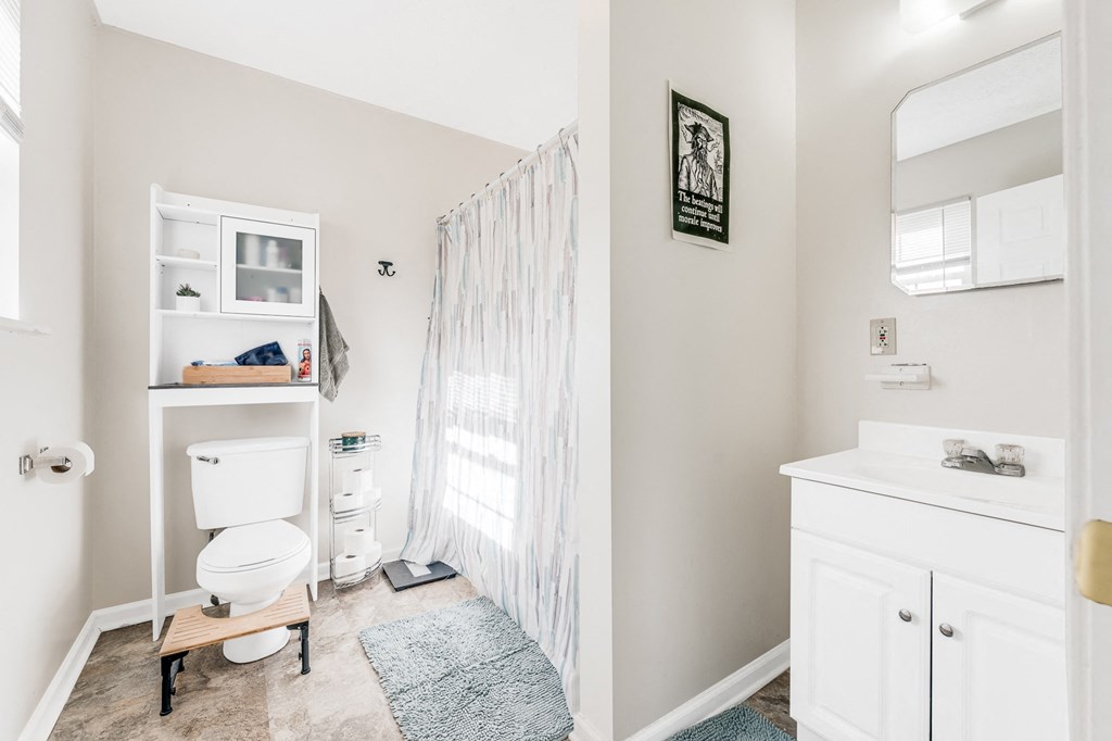 A bathroom with a toilet, sink, and a mirror.