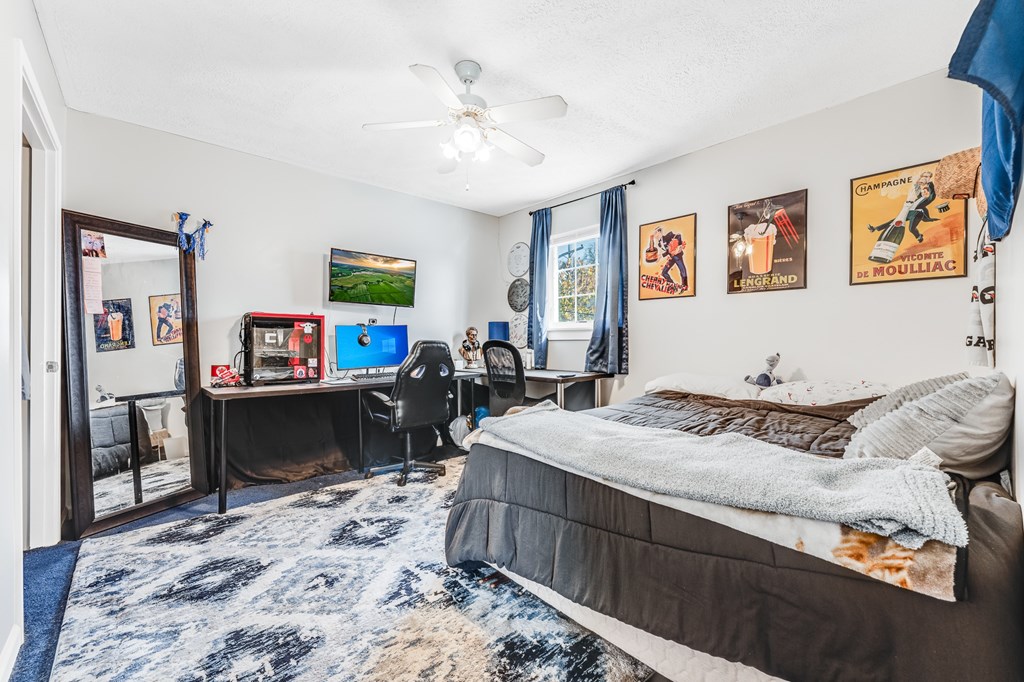 A bedroom with a bed, desk, and chair.
