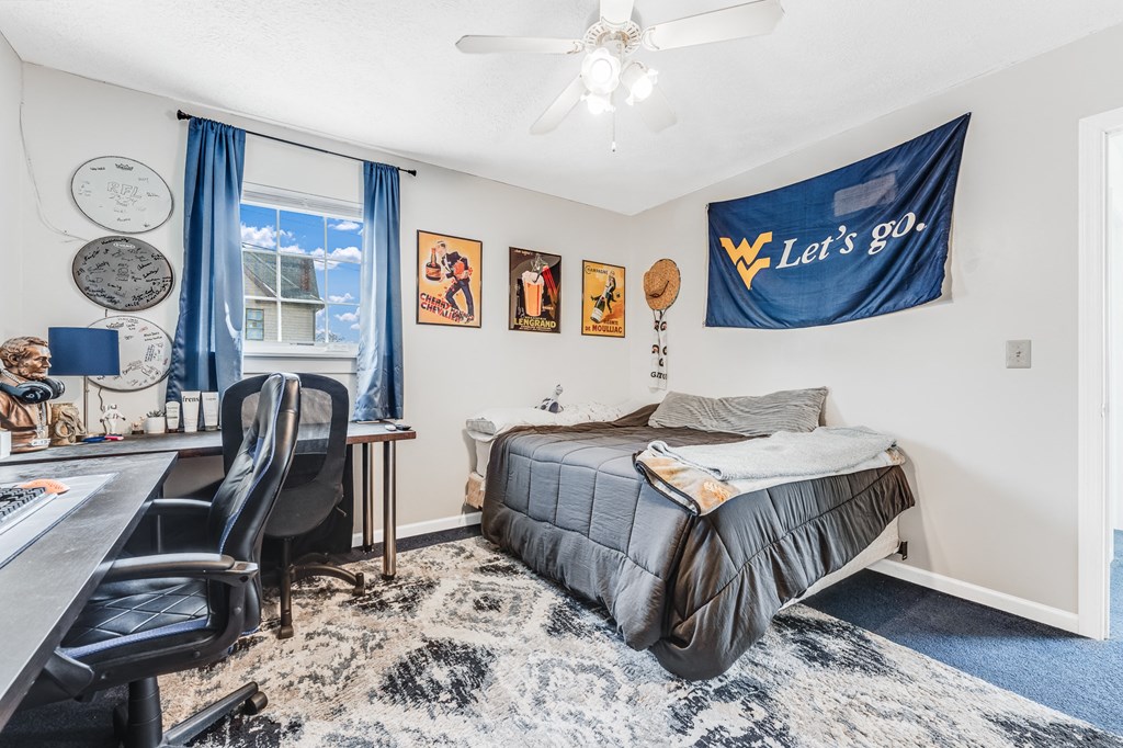 A bedroom with a bed, desk, chair, and wall decor.